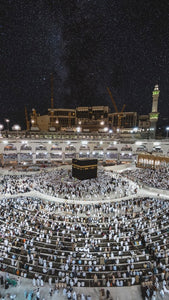 Vue aérienne de la maison sacrée à La Mecque en pleine nuit et en présence de pèlerins faisant la prière islamique.